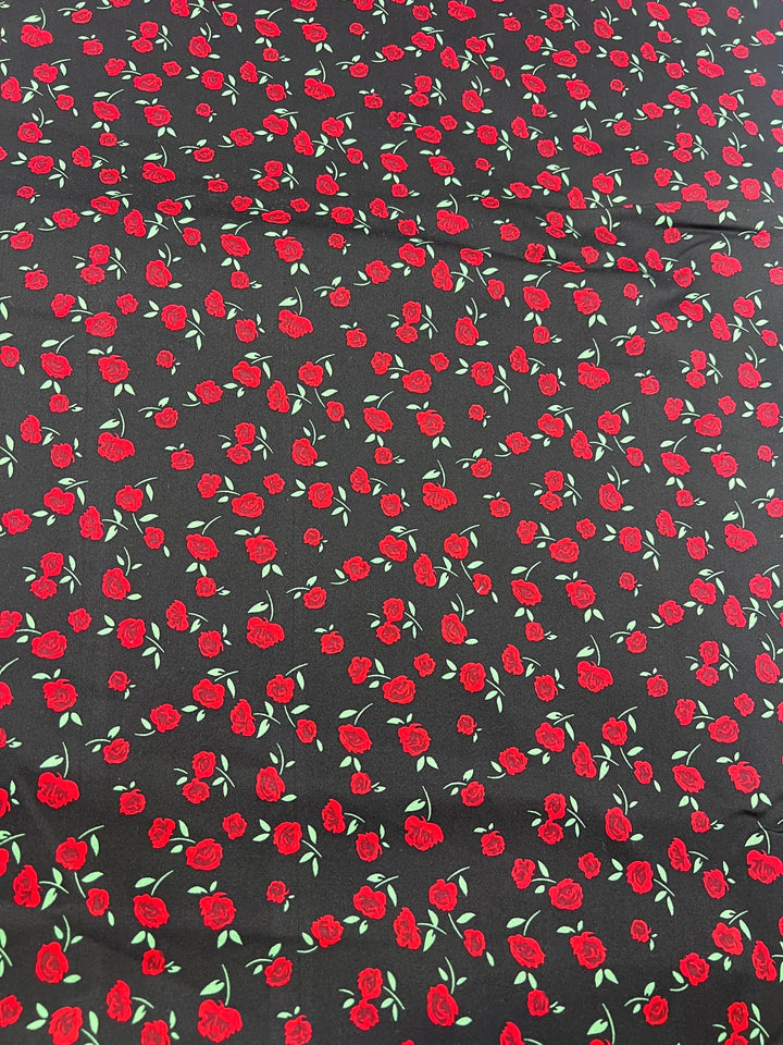 The "Cotton Sateen - Rosely - 125cm" by Super Cheap Fabrics is a medium-weight fabric featuring small red roses and green leaves, ideal for household décor projects.