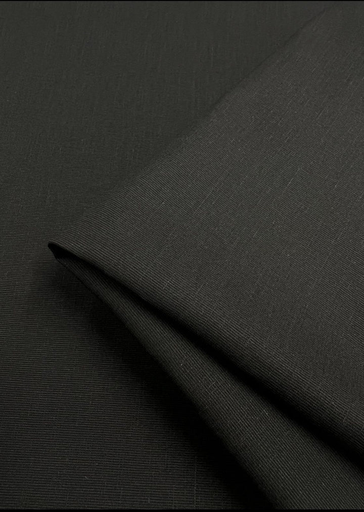 A close-up of Super Cheap Fabrics' Blended Viscose Suiting in black reveals a subtle textured weave, perfect for fancy dresses. The lighting highlights the smooth surface and soft texture of this 150cm drapey fabric.