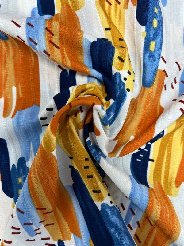 The Textured Deluxe Print - Stroke & Speck 1.0 by Super Cheap Fabrics features a vibrant combination of abstract brushstroke patterns swirled into a spiral on colorful polyester fabric. This design showcases shades of orange, blue, yellow, and white, creating an artistic scene that adds designer flair to any project. Measuring 155cm wide, this versatile fabric is perfect for various creative endeavors.