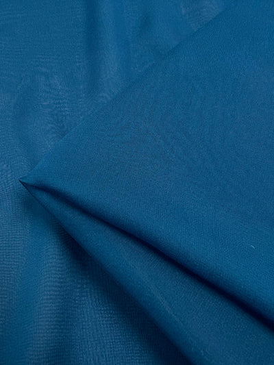 A close-up of a neatly folded piece of Silk Georgette in the Celestial colorway from Super Cheap Fabrics. This lightweight spring-summer fabric has a smooth texture with subtle patterns visible upon close inspection. The color appears uniform throughout the 135cm wide material.