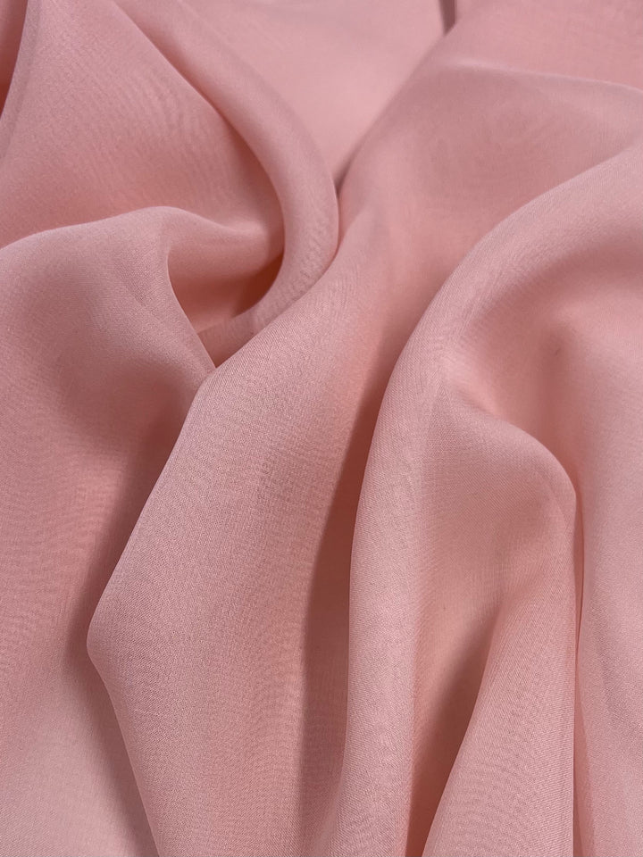 A close-up of Pure Silk Georgette in Pink Lotus from Super Cheap Fabrics shows soft, delicate folds and a smooth texture. The 135cm fabric resembles silk georgette with flowing material that creates subtle shadows and highlights.