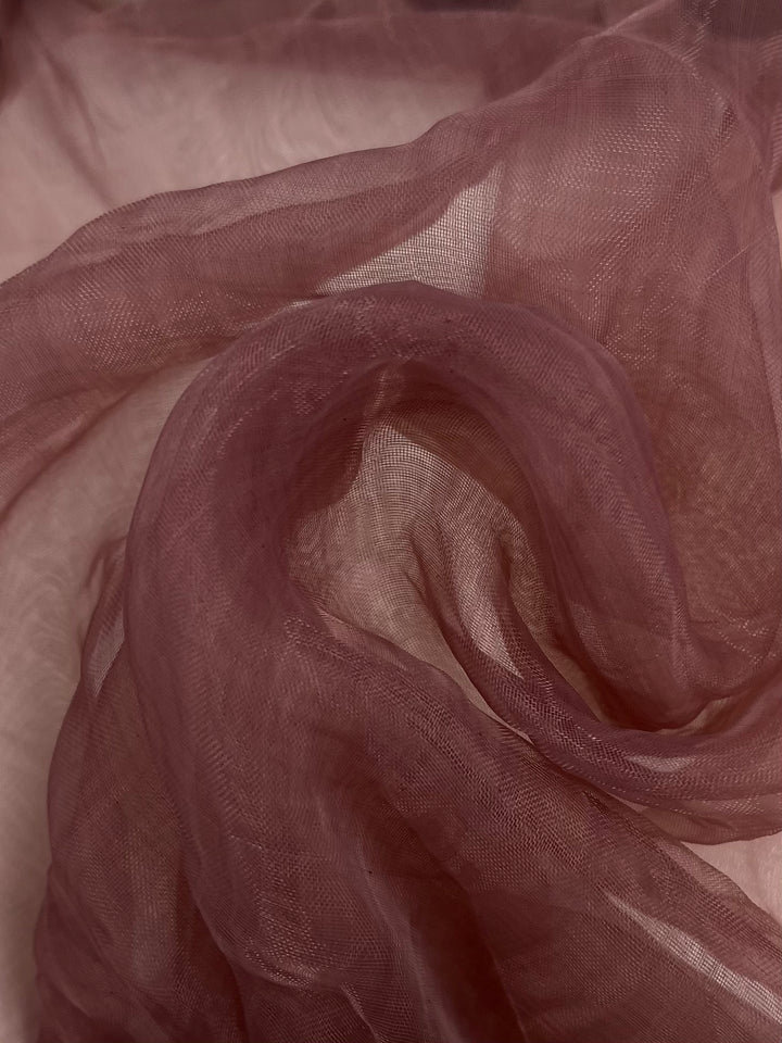 A close-up of the Organza fabric in Rose Tan by Super Cheap Fabrics, showcasing its sheer and flowing polyester texture. The material is layered and softly folded, with delicate details that convey movement and softness, while subtle shadows enhance its elegant appearance.