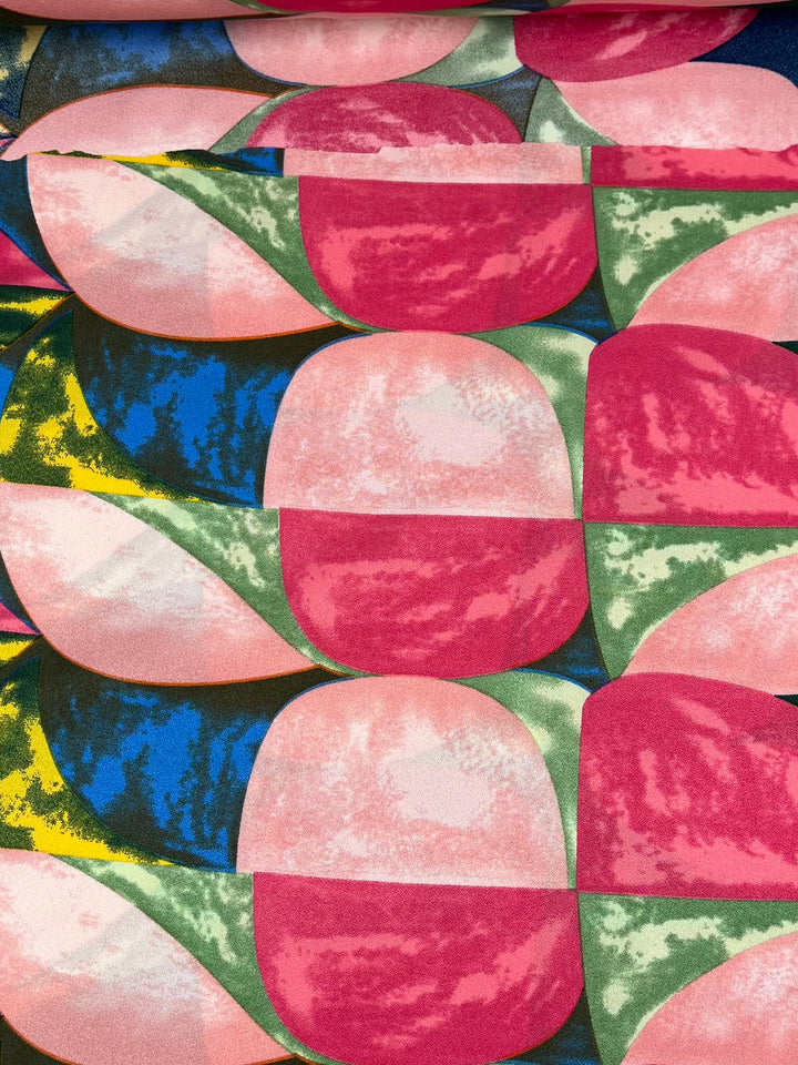 The Printed Crepe - Watermelon by Super Cheap Fabrics is a multi-use polyester fabric with a colorful abstract geometric pattern of overlapping rounded shapes in pink, green, blue, and yellow. Ideal for high fashion applications and measures 150cm wide.