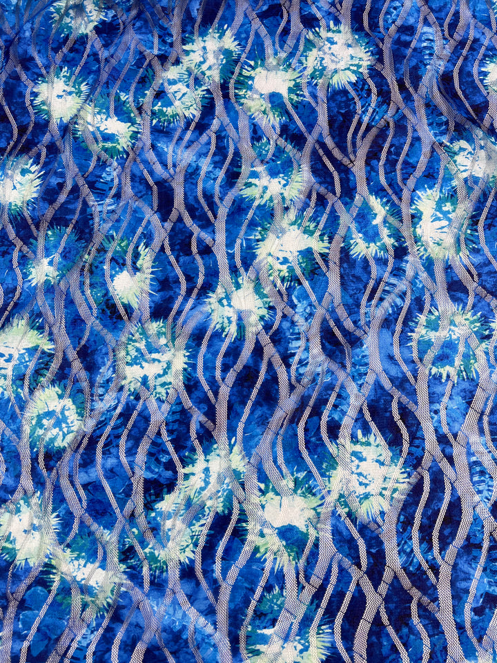 The Designer Textured Mesh - Ursula from Super Cheap Fabrics features a blue and white abstract pattern with wavy lines and starburst shapes, creating a textured effect on lightweight polyester fabric.