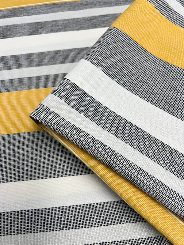 Striped fabric with a pattern that alternates between broad yellow, gray, and white horizontal stripes. The gray stripes have a fine mesh-like texture. Part of the Designer Cotton Range, this sustainable deadstock material is neatly folded on a larger piece of the same design. Introducing Designer Cotton - Monaco - 145cm by Super Cheap Fabrics.