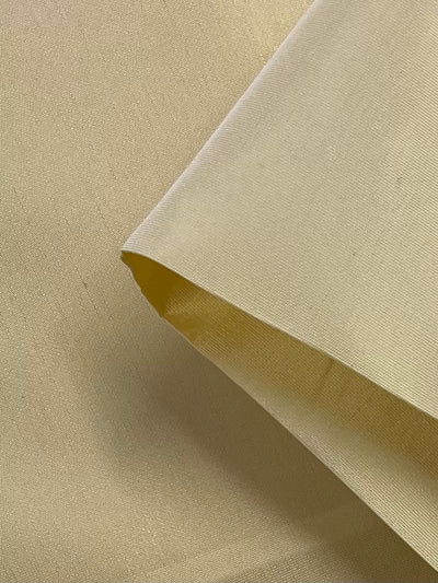 Close-up of folded Banana Taffeta by Super Cheap Fabrics, a 150cm wide fabric made from 100% polyester. Its smooth texture and diagonal positioning highlight its lightweight nature, consistent color, thickness, and weave pattern for a uniform appearance.