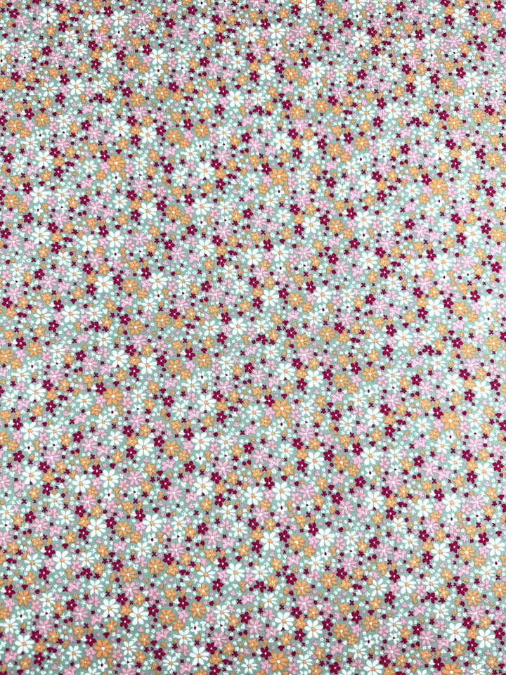 The Soft Cotton - Cluster - 140cm from Super Cheap Fabrics features a vibrant floral pattern with small flowers in shades of pink, purple, orange, and white on a light background. Made from soft cotton, this breathable fabric offers a textured effect ideal for your summer fabric needs.