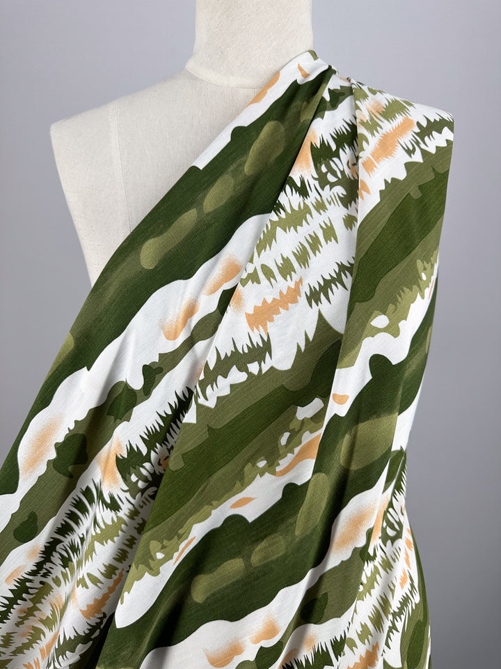 Super Cheap Fabrics’ Bamboo Rayon - Torn Camo - 150cm is a lightweight fabric in green, white, and tan abstract camo, shown on a torso mannequin against a gray background—ideal for beginner sewing projects.