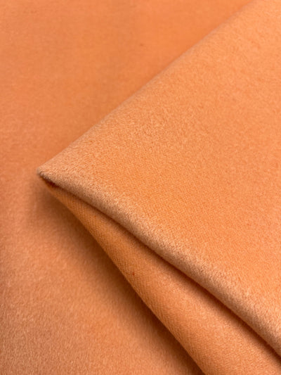 Close-up of Super Cheap Fabrics' Wool Cashmere in Coral Sands, 150cm width. The peach hue and soft texture create gentle shadows and highlights.