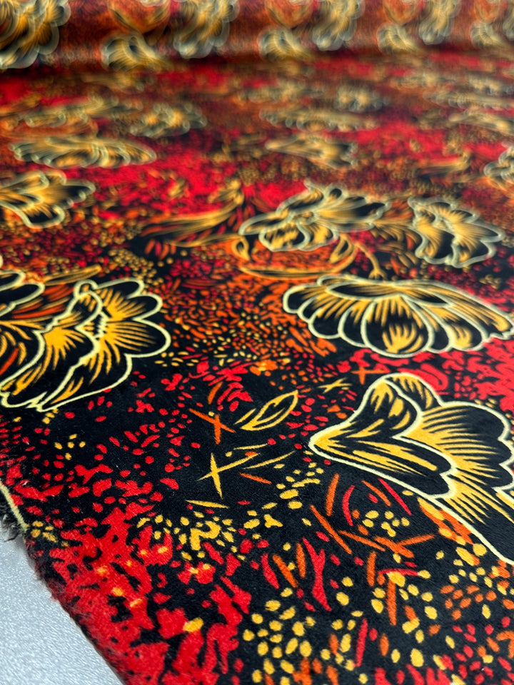 Close-up of DD Velvet - Ember Bloom (150cm) by Super Cheap Fabrics, showcasing vibrant yellow and orange floral designs on a bold black and red speckled background.