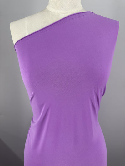 A dress form displays a fitted, one-shoulder garment made from Super Cheap Fabrics ITY Knit - Iris Orchid (150cm), shown against a plain gray background.