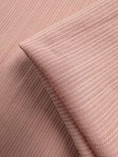 Close-up of Super Cheap Fabrics' Textured Cotton in Gossamer Pink (138cm), featuring soft, diagonally ribbed patterns and a neatly folded edge overlapping the background.