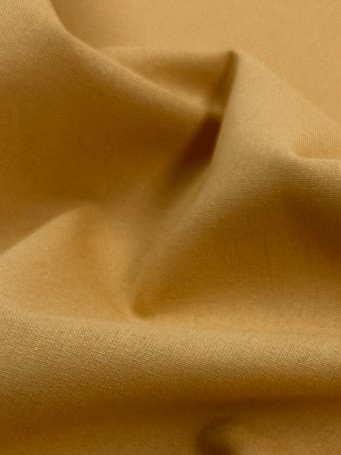 A close-up of Inca Gold Ramie Linen by Super Cheap Fabrics shows its soft texture and natural drape with gentle folds and subtle shadows, capturing the fabric's smoothness. .