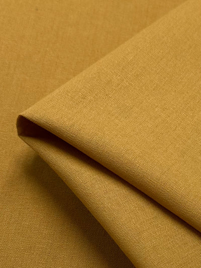 Close-up of a folded piece of the "Ramie Linen - Inca Gold - 150cm" by Super Cheap Fabrics, highlighting the charm of its subtle texture and natural fibers.