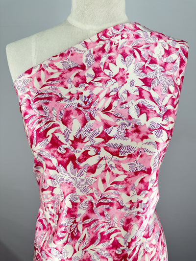 A mannequin showcases a chic sleeveless one-shoulder dress made from Super Cheap Fabrics' Silky Satin - Lotus. The lightweight fabric features an elegant pink and white abstract floral pattern with leaf-like designs on a light background.