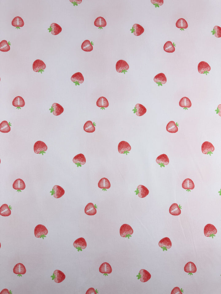 The "Printed Cotton - Tutti Fruity" from Super Cheap Fabrics features a light pink background adorned with a pattern of small, evenly spaced strawberries on lightweight cotton fabric. The fabric measures 150cm in width.