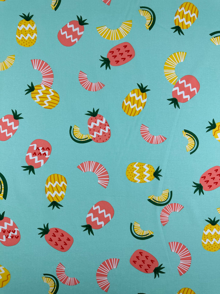 The Printed Cotton - Pina Coalda - 150cm by Super Cheap Fabrics showcases a turquoise background adorned with vibrant pink and yellow pineapples and semicircles accented by white zigzag lines. Made from natural cotton fibers, this lively and colorful design is perfect for creating bright and cheerful clothing and household items.