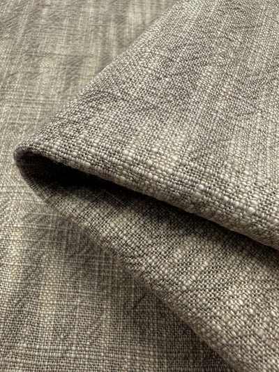 Super Cheap Fabrics' Basket Dyed Cotton in Taupe - 140cm features a folded textured upholstery fabric with shades of light gray and beige, offering a durable cotton blend with a subtle woven pattern.