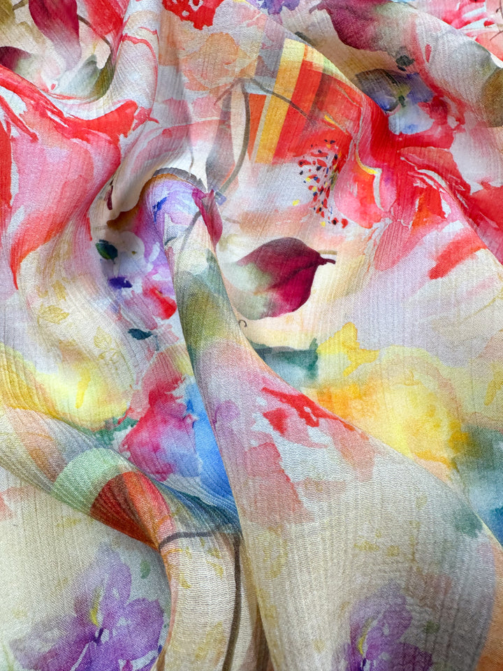 A close-up of the Designer Cotton - Reflection - 150cm by Super Cheap Fabrics, featuring a vibrant floral pattern in shades of red, pink, yellow, and purple. This fabric drapes softly to create delicate folds and shadows, making it ideal for luxury sewing projects.