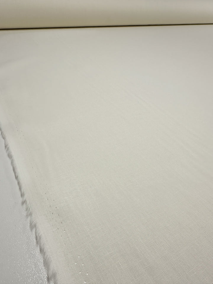 A close-up view of the Pure Linen - Ivory - 138cm by Super Cheap Fabrics, showcasing its large and smooth lightweight linen fabric with an ivory sheen. The slightly visible texture and soft edge runs across the image on the left side.