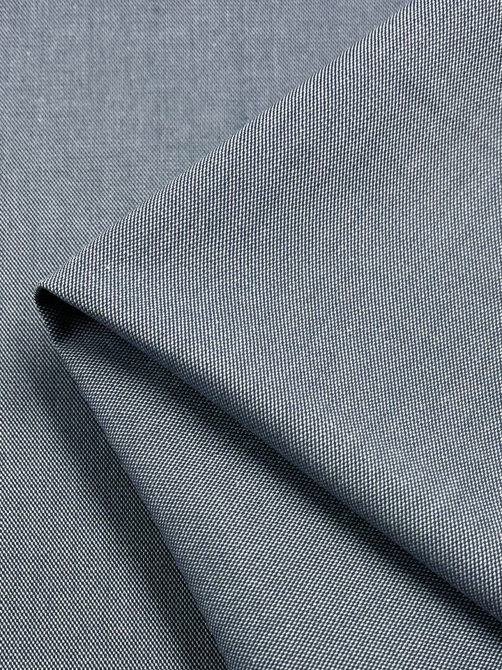 Close-up of a folded piece of black houndstooth fabric. The intricate check pattern highlights the versatility and classic design of Super Cheap Fabrics' Suiting - Eventide - 135cm, pairing beautifully with twill suiting.