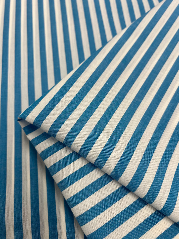 Super Cheap Fabrics' Cotton Lawn - Vivid Blue (150cm) is a blue and white striped, lightweight cotton fabric with a silky finish, folded neatly.