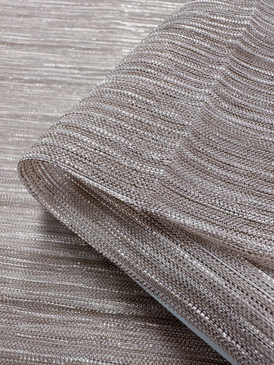 Presenting a close-up of the Metallix Pleat - Blush fabric by Super Cheap Fabrics, showcasing its shimmering silver mesh with a textured and glittery appearance. This lightweight polyester is elegantly folded, highlighting its semi-transparent quality accompanied by a subtle blush tint. Measuring 140 cm in width, it's perfect for adding a touch of elegance to your creations.