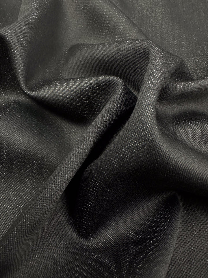 A close-up of the Stretch Denim - Raven by Super Cheap Fabrics reveals its elegant sheen and smooth, slightly crumpled texture, highlighting its sophisticated drape reminiscent of lightweight denim.