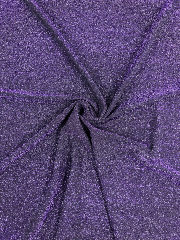 A swirling close-up of the Metallic Lycra - Disco Plum fabric by Super Cheap Fabrics showcases its purple shimmery texture. The glimmering surface highlights the material, creating a spiral effect at the center that evokes the elegance of dresses and tops.