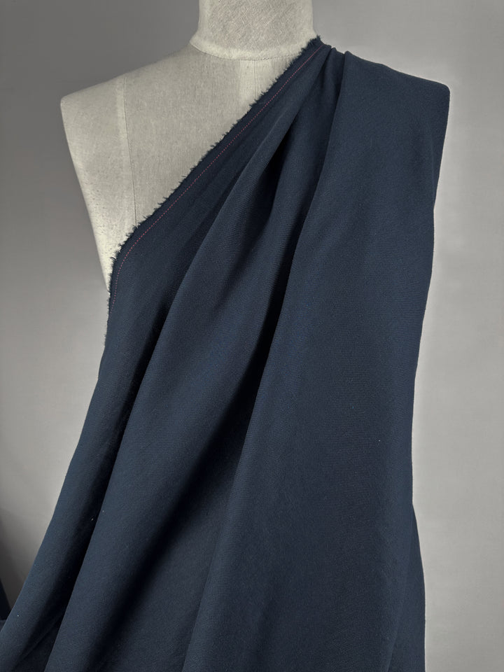 A mannequin draped in Pure Washed Linen - India Ink from Super Cheap Fabrics highlights its smooth, slightly textured surface and fluid fall, wrapping diagonally against a neutral background.