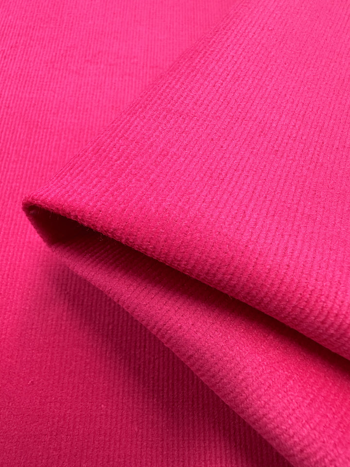 Close-up image of Super Cheap Fabrics' Micro Wale Corduroy in Beetroot Purple, 137cm wide, with a ribbed texture. The layers highlight its thickness and softness, while the rich color and slight fuzziness make it ideal for warm, cozy winter clothing.