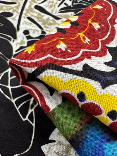 The Linen Blend - Wonky Patchwork by Super Cheap Fabrics features vibrant red, yellow, and blue floral and abstract patterns on a black and white background. This lightweight linen is perfect for adding color to your home decor. Width: 145cm.