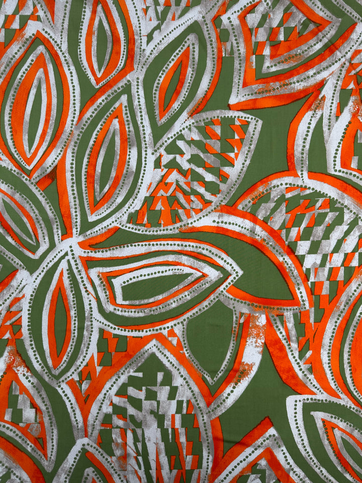 The "Printed Lycra - Papaya - 150cm" by Super Cheap Fabrics features a colorful abstract pattern with large, overlapping leaf-like shapes in orange, green, and white. Made from medium-weight Polyester/Spandex fabric, it boasts intricate details and checkered sections for a vibrant effect.