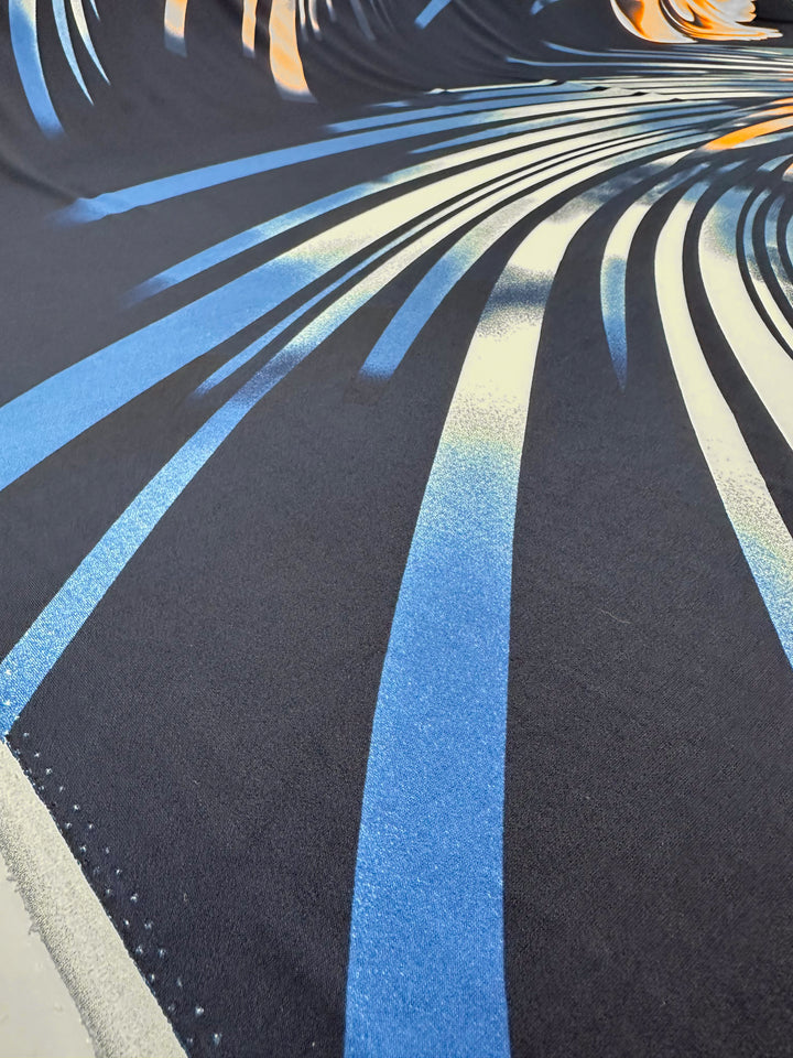 The product "Printed Lycra - Bold - 150cm" by Super Cheap Fabrics features an abstract image with dynamic blue and orange curved stripes on a dark background, evoking flexibility and movement similar to a two-way stretch for added depth.