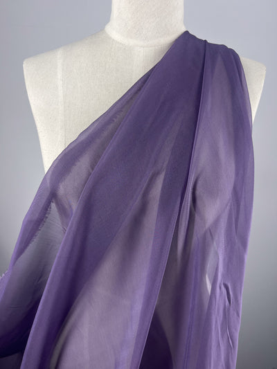 Set against a plain gray background, the mannequin is elegantly adorned with the Silk Mousseline - Currant from Super Cheap Fabrics. This sheer, extra lightweight fabric drapes gracefully over one shoulder, its delicate translucence partially covering the torso and highlighting its exquisite texture.