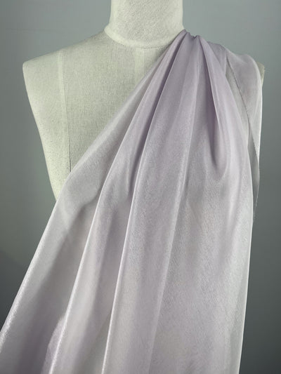 The Silk Mousseline - Orchid by Super Cheap Fabrics, featuring a subtle metallic shimmer, is elegantly draped over a white mannequin against a neutral gray background, showcasing its flowing and timeless beauty.