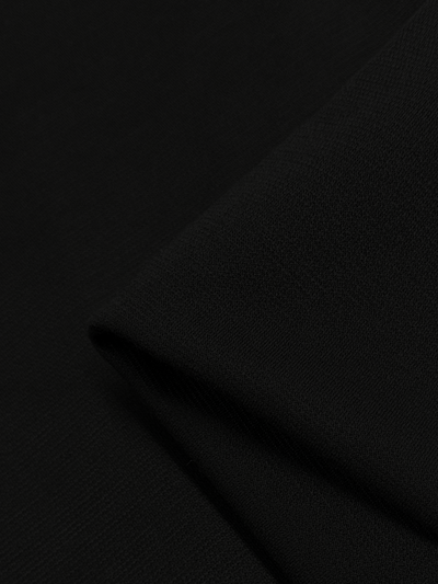 A close-up image of the Waffle Knit - Black fabric from Super Cheap Fabrics, showcasing its smooth texture and slight folds. The intricate waffle knit pattern appears to have a subtle sheen, demonstrating high-quality craftsmanship and adding a three-dimensional effect.