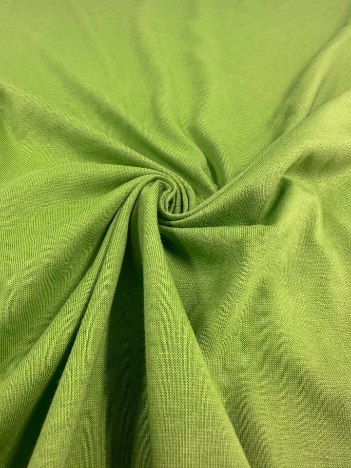 A close-up of the Cotton Jersey - Titanite - 160cm by Super Cheap Fabrics twisted into a spiral, showing a textured swirl pattern with smooth fabric and subtle shading variations, adding depth to the image.