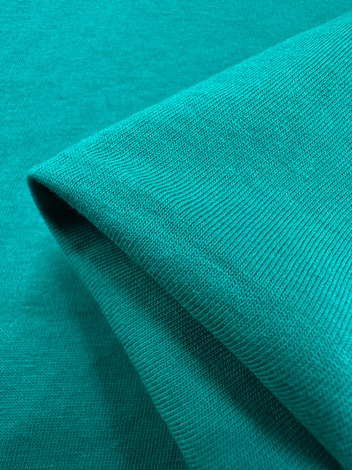 Close-up of folded Cotton Jersey - Kayaking by Super Cheap Fabrics, featuring textured turquoise cotton with fine knit details and a soft, smooth appearance, ideal for crafting lightweight jersey jumpsuit dresses. Width: 155cm.