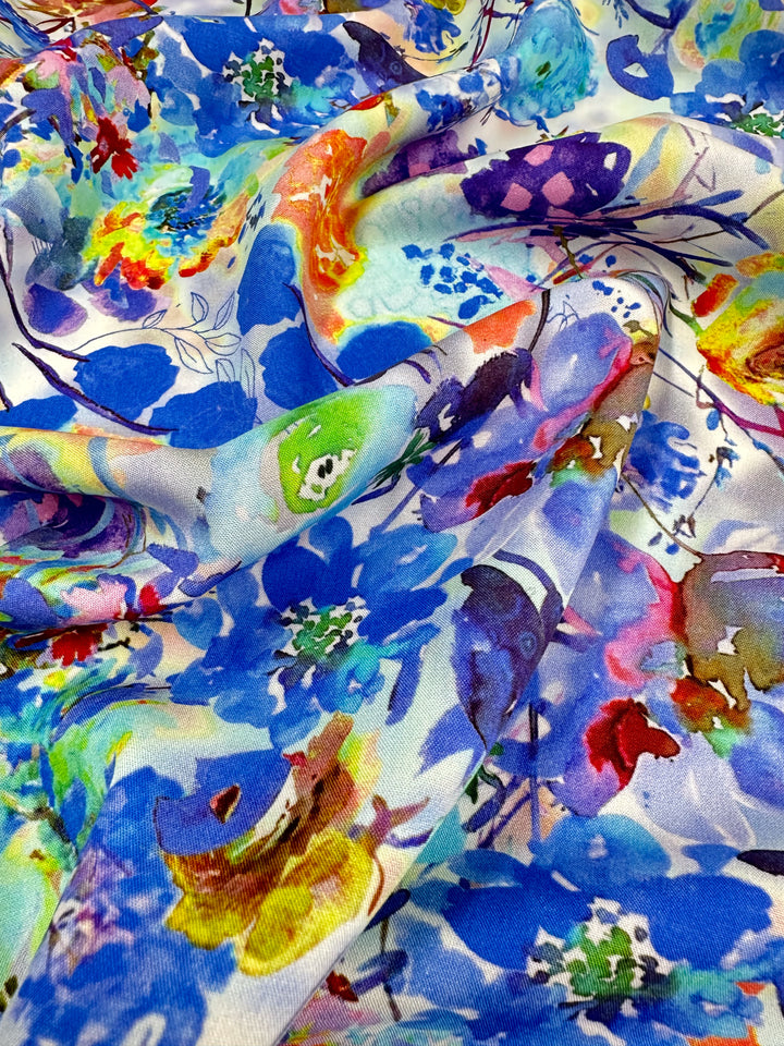 The Designer Rayon - Cortney by Super Cheap Fabrics is a versatile multicolored floral fabric featuring abstract blue, green, red, orange, and purple flowers on a slightly wrinkled texture.