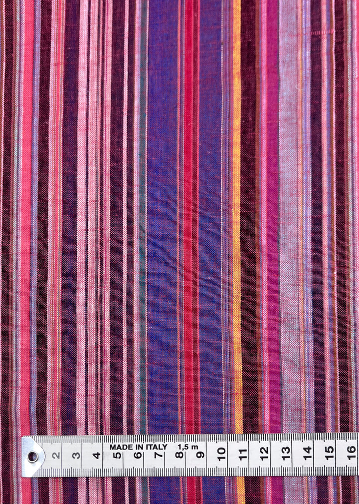 The Linen Blend - Goa by Super Cheap Fabrics features a vibrant, vertically striped, yarn-dyed design in shades of red, pink, purple, and blue. A ruler marked with centimeters at the bottom hints at its vintage Italian craftsmanship. The fabric is 150cm wide.