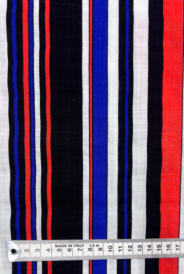 A close-up view of Super Cheap Fabrics' Linen Blend - Minimal showcases its lightweight fabric with vertical stripes in red, white, blue, and black. For scale, a measuring tape displaying centimeters is placed horizontally across the bottom.