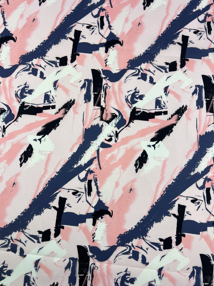 The Peaches & Cream printed cotton by Super Cheap Fabrics showcases a dynamic abstract pattern with pink, black, and white brushstrokes, resembling an art piece with bold lines and splatters. Its lightweight fabric is 150cm wide.