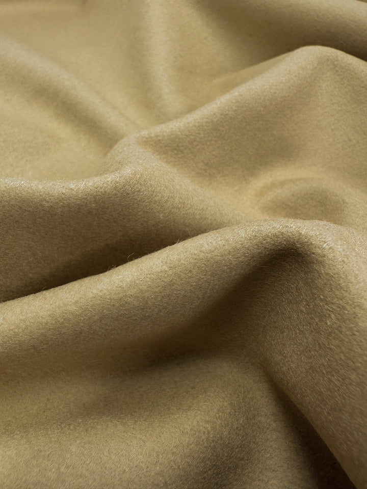 A close-up of Super Cheap Fabrics' Merino Wool - Curd & Whey, 150cm, showcases its soft beige texture with smooth folds that create a luxurious play of light and shadow.