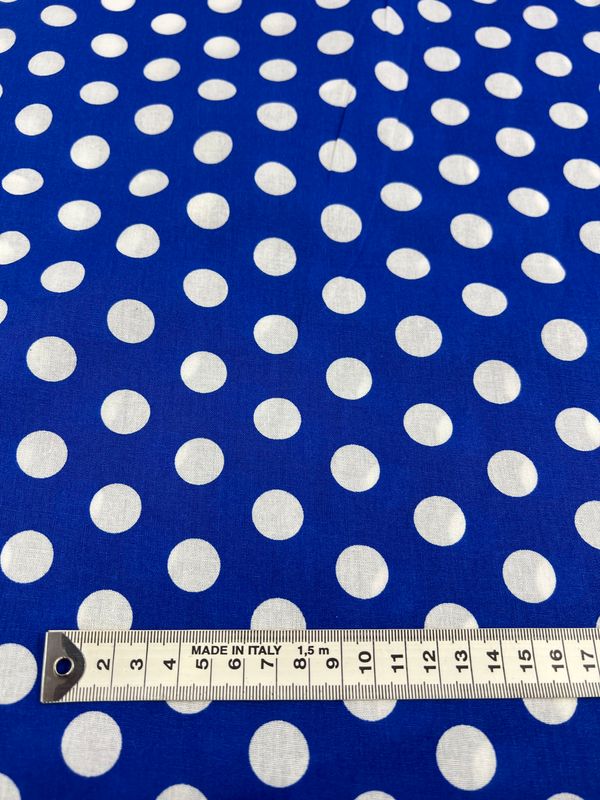 A close-up of Super Cheap Fabrics' Linen Blend - Dazzling Blue - 112cm fabric with white polka dots, featuring a measuring tape at the bottom showing various measurements.