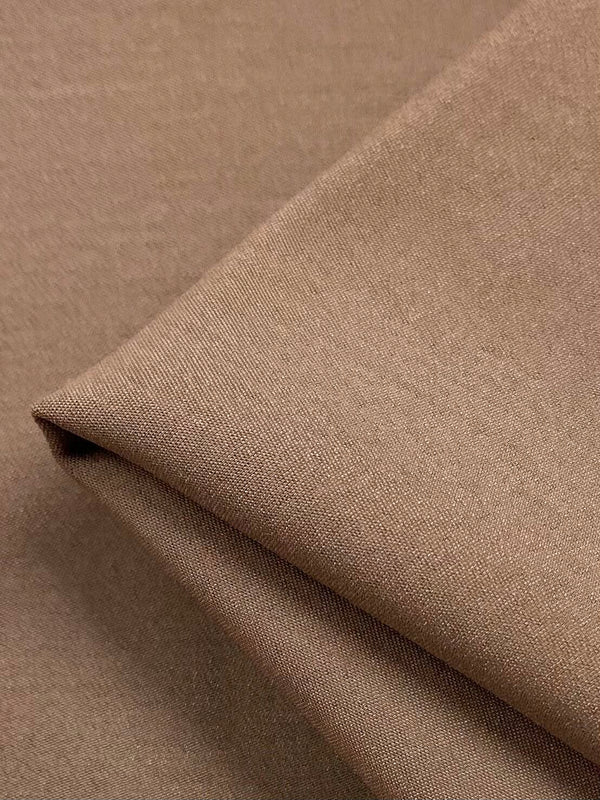 A close-up of the Stretch Viscose Suiting in Tawny Brown from Super Cheap Fabrics shows its smooth texture and matte finish. The tightly woven 125cm fabric blends viscose for a soft feel, with gentle folds creating depth and subtle shadows.