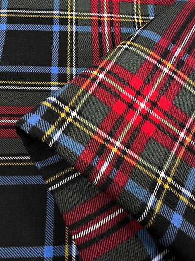 A close-up image of two folded tartan Printed Bengaline fabrics by Super Cheap Fabrics highlights their intricate plaid designs: one in red, black, and green; the other in blue, black, and green. Both feature intersecting white and yellow lines on a medium-weight 150cm fabric.