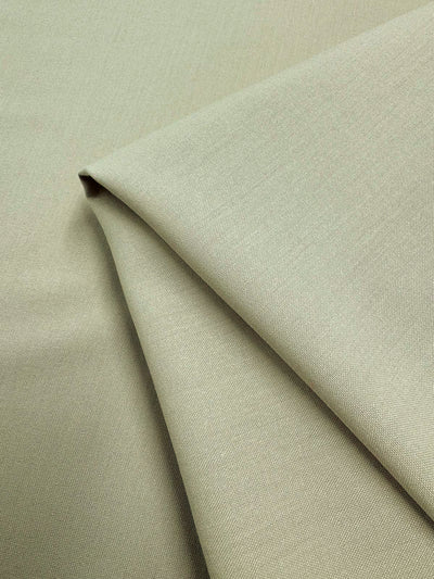 A close-up of Deluxe Suiting - Brown Rice (150cm) by Super Cheap Fabrics shows light beige, medium weight polyester fabric, neatly folded with a smooth texture and subtle brown rice weave.