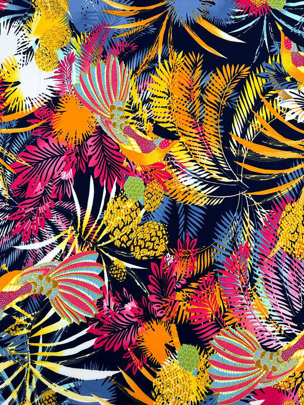 The "Printed Lycra - Jumba - 150cm" by Super Cheap Fabrics features a vibrant and colorful pattern with overlapping tropical leaves and flowers in bright shades of yellow, orange, pink, red, green, and blue. The design is printed on Lycra fabric against a dark blue background, creating a vivid and eye-catching contrast with beautiful prints.