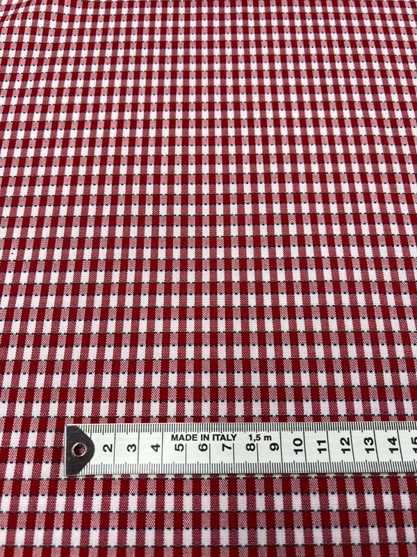 A close-up of the Shirting - Riding - 145cm fabric from Super Cheap Fabrics, made of red and white gingham polyester with a small checkered pattern. A measuring tape shows length up to 5 centimeters. This lightweight, multiuse fabric is labeled "Made in Italy.